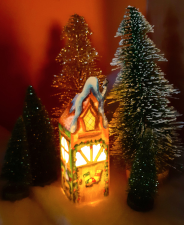 Une maison de Noël en papier en 3D, illustrée à l'aquarelle avec une bougie à l'intérieur.